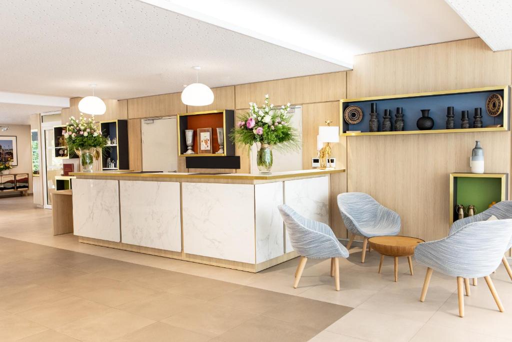 a lobby with a counter with blue chairs and a table at Residhome Toulouse Ponts Jumeaux in Toulouse
