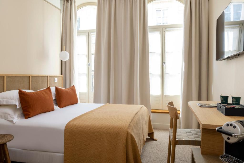 a bedroom with a bed and a desk and windows at Hôtel Joe M in Paris