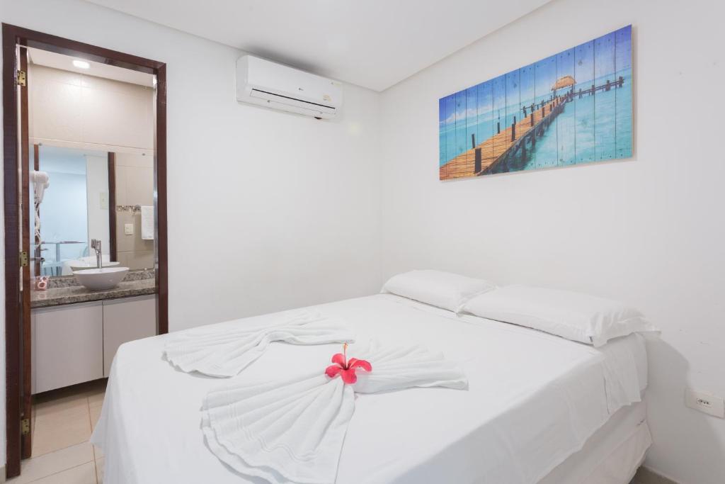 - une chambre blanche dotée d'un lit blanc avec une arche rose dans l'établissement Condomínio Belas Praias, à Porto de Galinhas