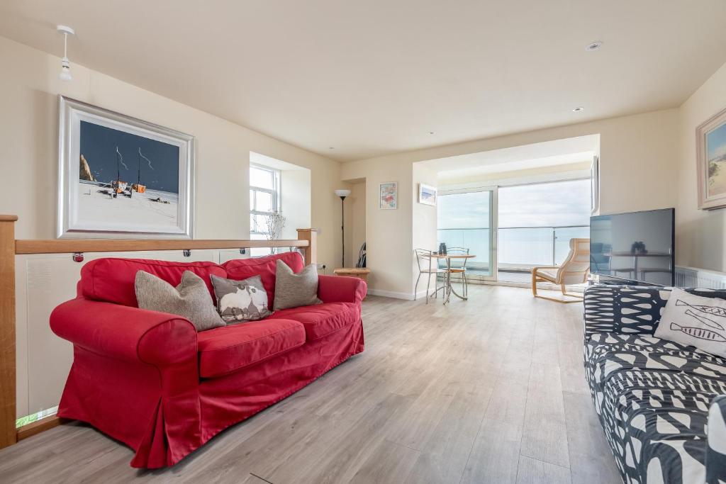 a living room with a red couch and a table at Stunning Shore Front house in historic Cellardyke in Anstruther