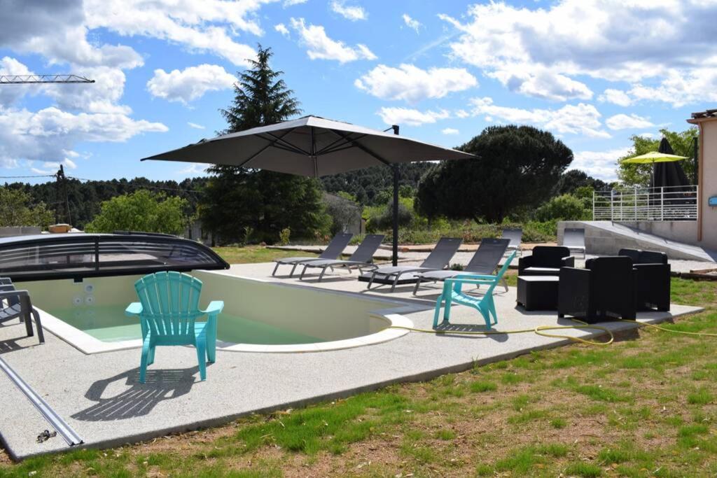 a swimming pool with chairs and an umbrella at Villa de charme avec piscine couverte et 3000m2 in Rosières