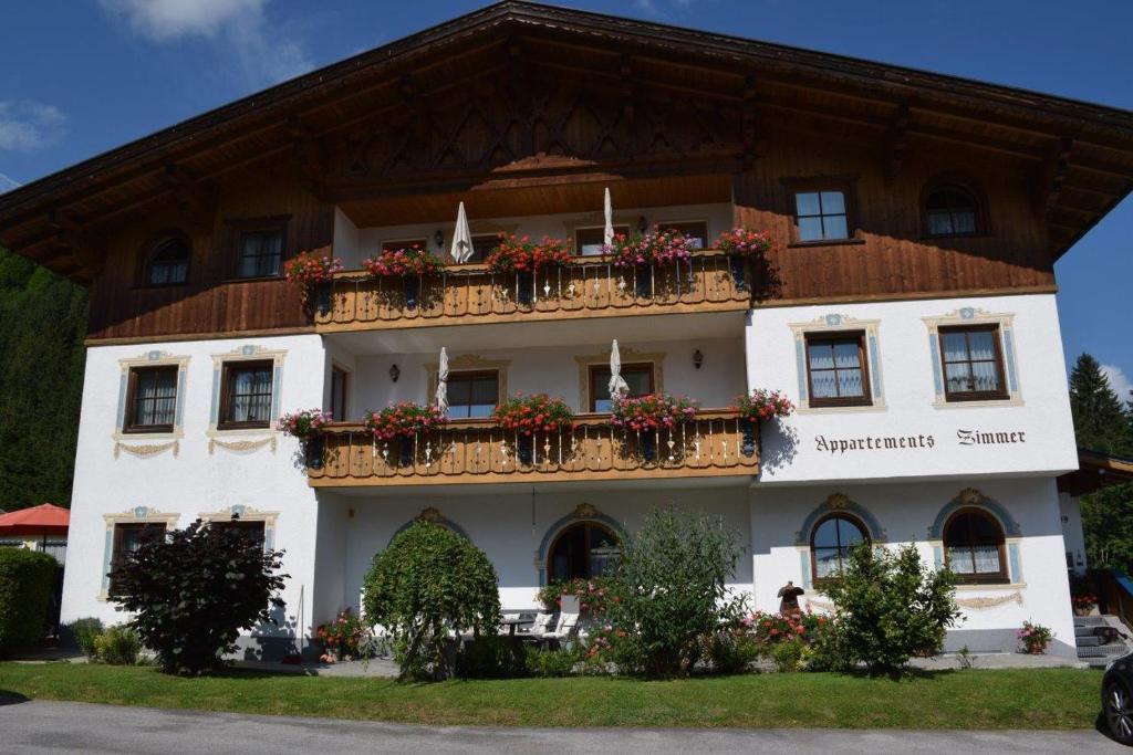 ein großes weißes Gebäude mit Blumen auf den Balkonen in der Unterkunft Landhaus Bichlbach in Bichlbach