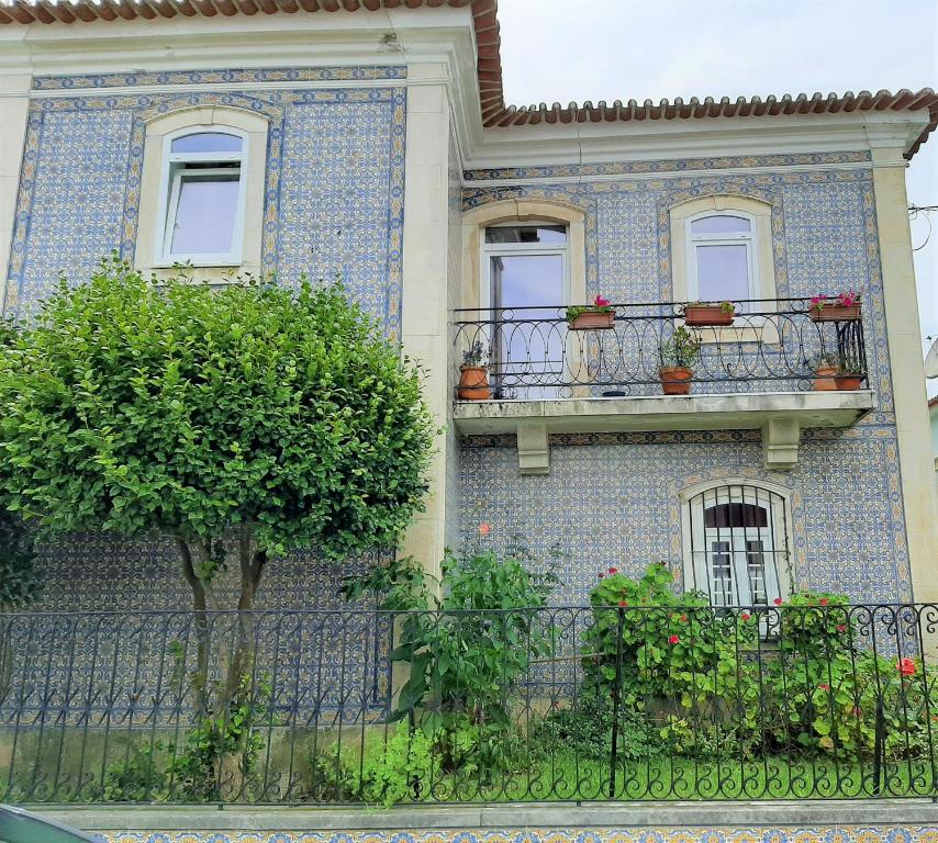 a building with two balconies and a tree at Casa das Camélias Garden Guesthouse in Aveiro