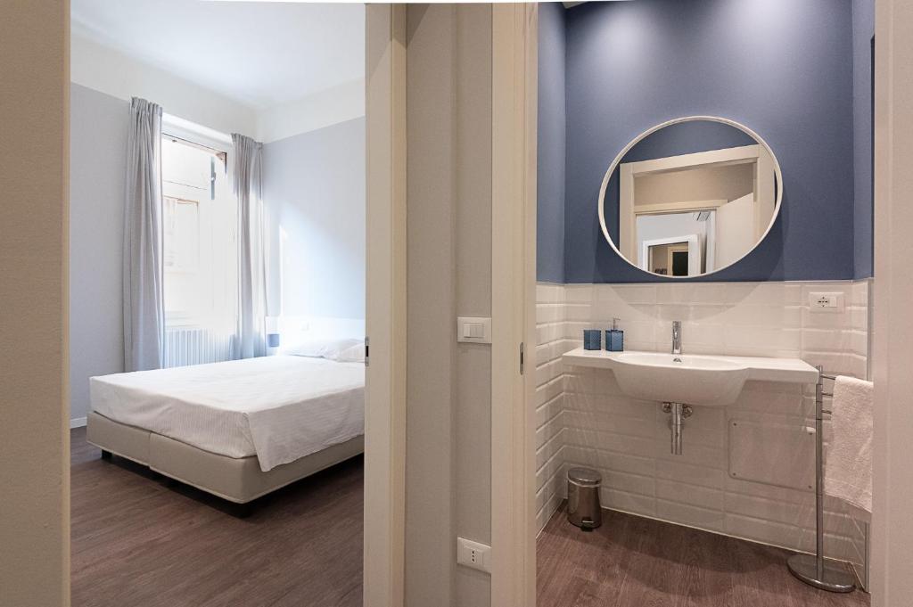un bagno con lavandino e specchio accanto a un letto di Good night Romeo - Eleganti Dimore a Verona
