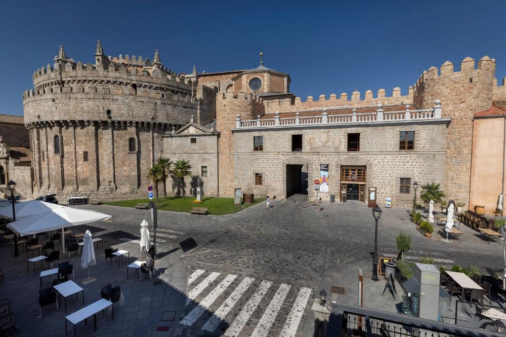 un grande edificio in pietra con un castello sullo sfondo di Hostal Restaurante Puerta del Alcázar ad Ávila