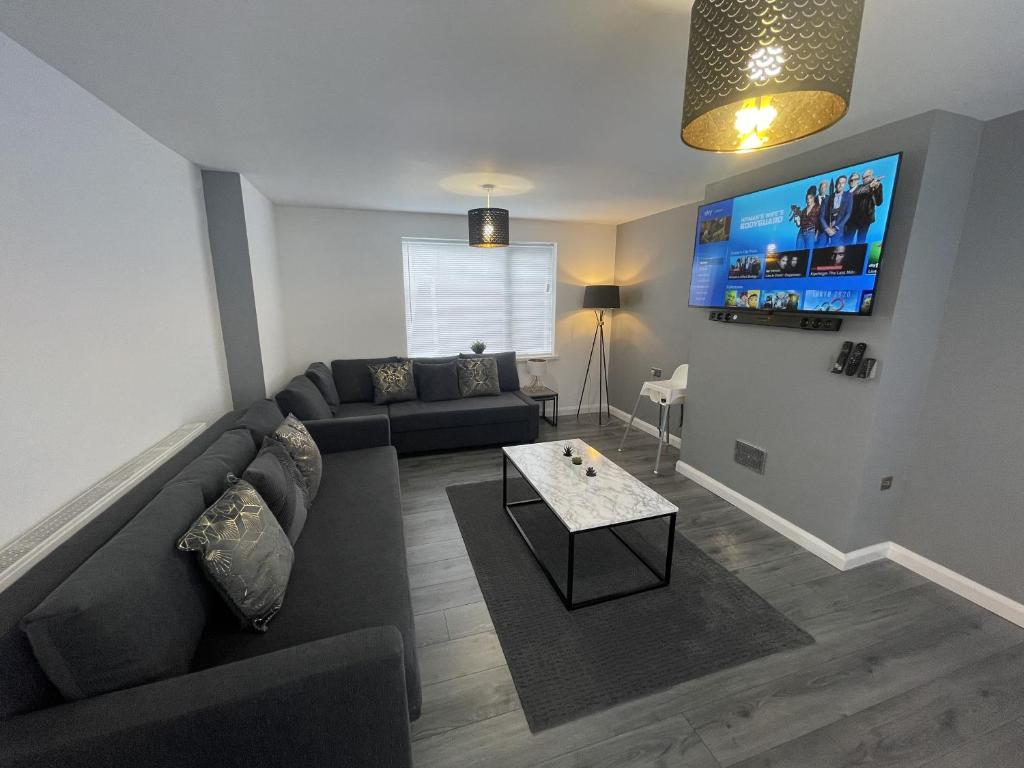 a living room with a couch and a tv at NEW Luxurious Modern Large 3 Bed House - Sleeps Up to 10 Guests - Sky Ultra HD, Sky Movies, Netflix, Disney Plus in Mansfield