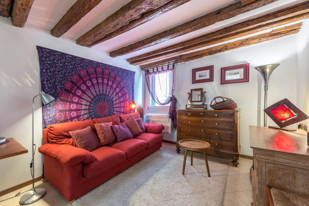 uma sala de estar com um sofá vermelho e uma cómoda em PICCOLO - Cozy studio in the heart of authentic Venice em Veneza