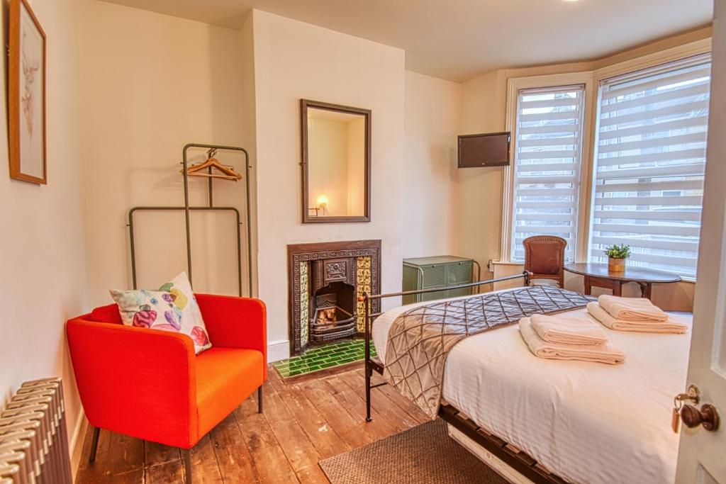 バースにある4 Bedroom House in central Bath with Garden & Free Private Parkingのベッドルーム(ベッド1台、椅子、暖炉付)