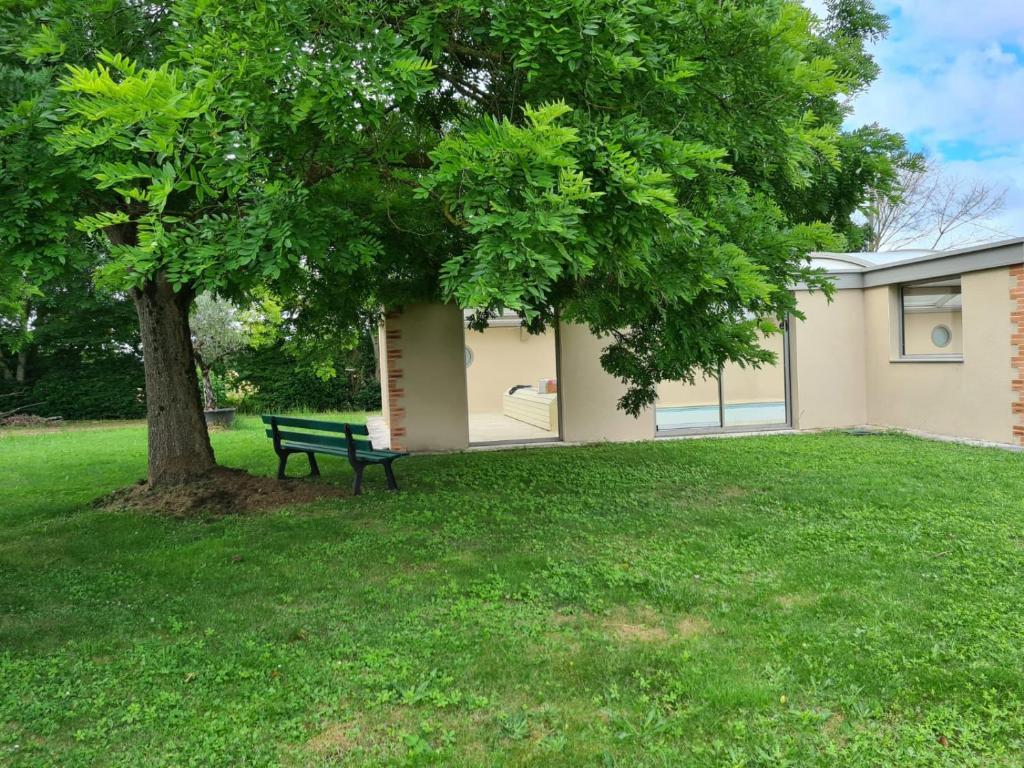 a park bench under a tree next to a building at Maison de vacances Daumeray in Daumeray