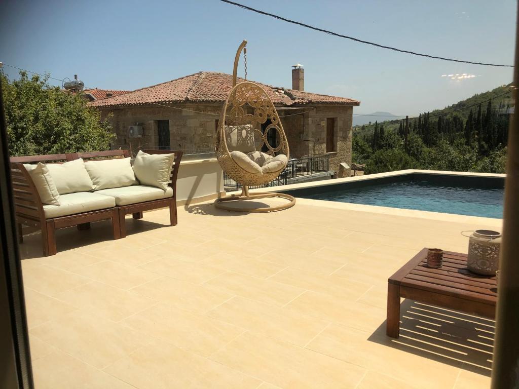 a patio with a chair and a swing next to a pool at Villagio inn Suite & Spa in Soúlion