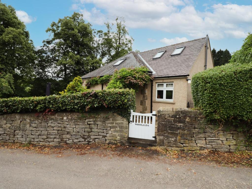 a house with a stone wall and a white gate at Woodlands in Matlock