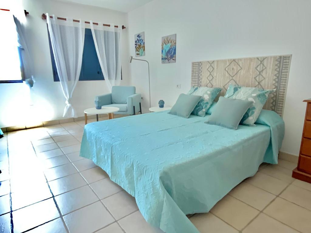 Un dormitorio con una gran cama azul con sábanas azules en Maresia Holiday House, en Caleta de Sebo