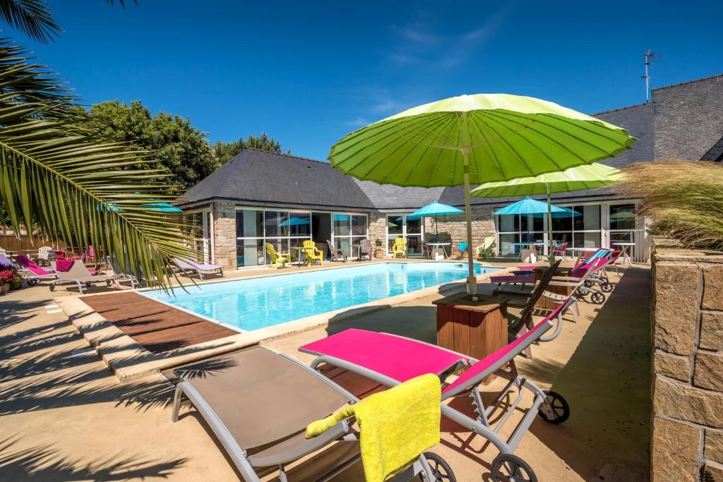 een zwembad met ligstoelen en een groene parasol bij L'Hippocampe in Plouharnel