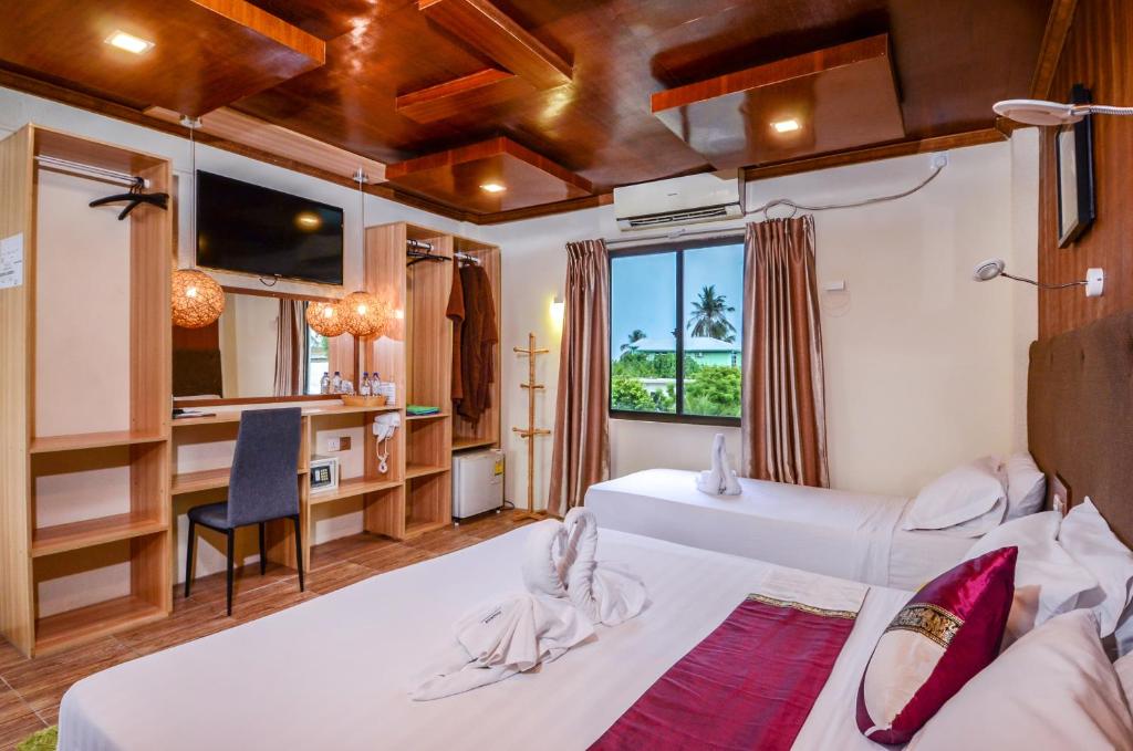 a hotel room with two beds and a desk at Summer Villa Guest House in Maafushi