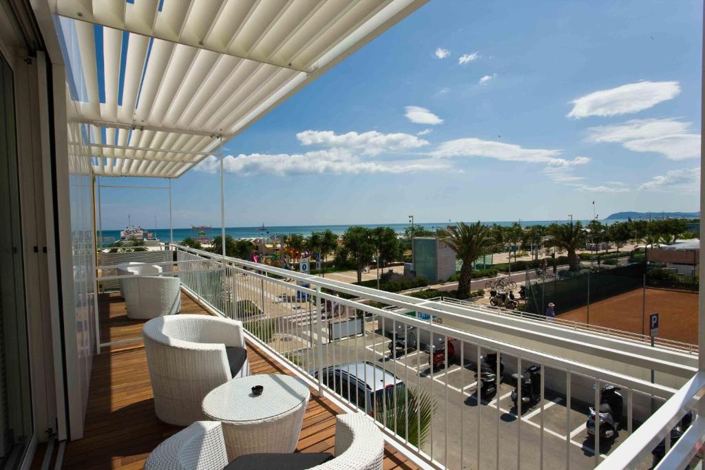 Un balcón con sillas blancas y vistas al océano. en Hotel Roma, en Riccione