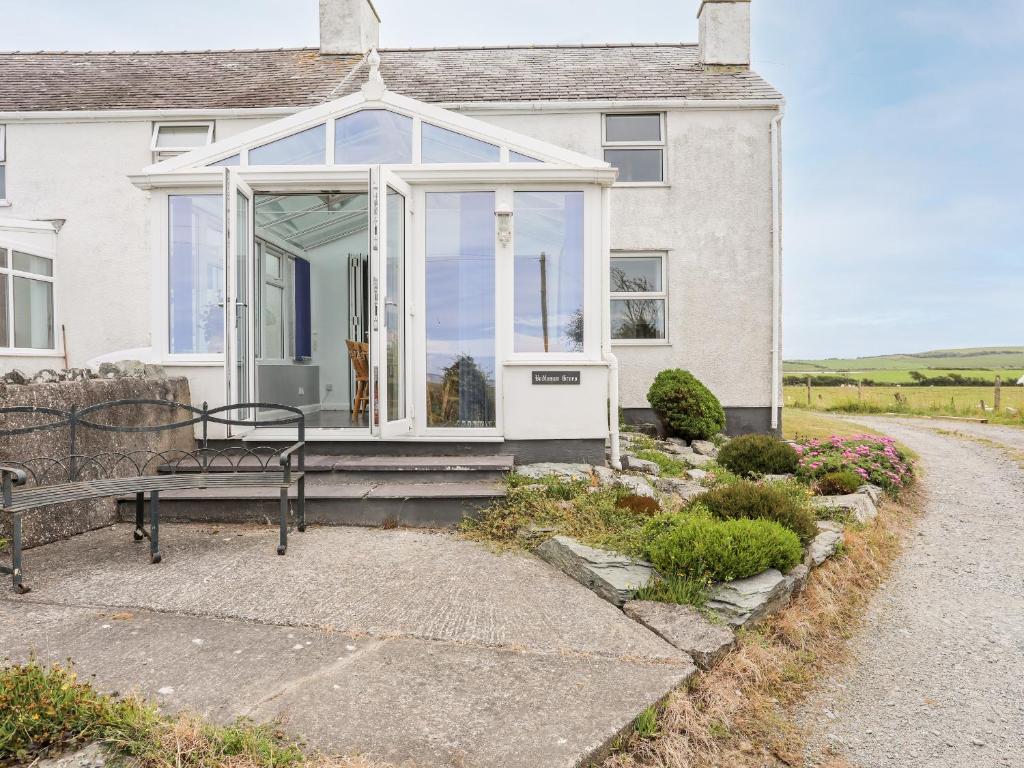 a white house with a bench in front of it at Bodlasan Groes Cottage in Holyhead