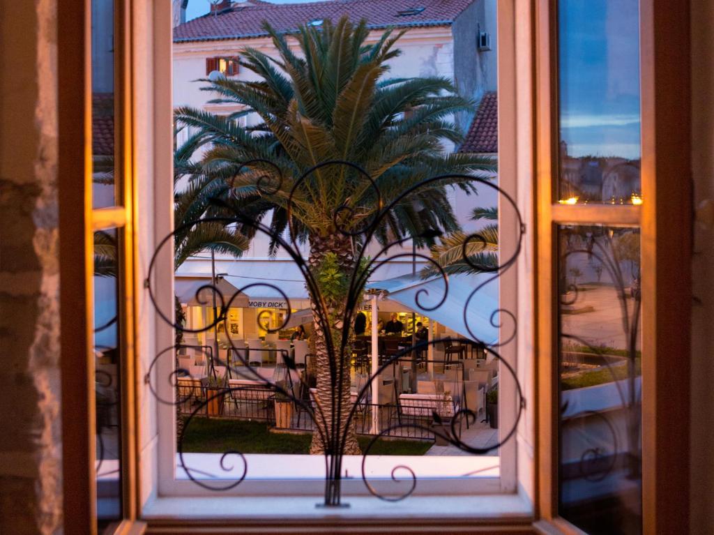 une fenêtre avec un palmier dans l'établissement Villa Lošinj, à Mali Lošinj