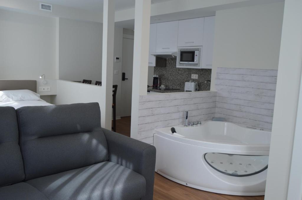 a bathroom with a tub and a chair and a bed at Apartamentos el Beyu in Cangas de Onís