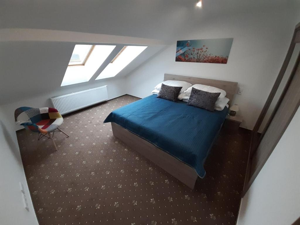 1 dormitorio con 1 cama con sábanas y almohadas azules en Apartmány Viecha, en Bardejov