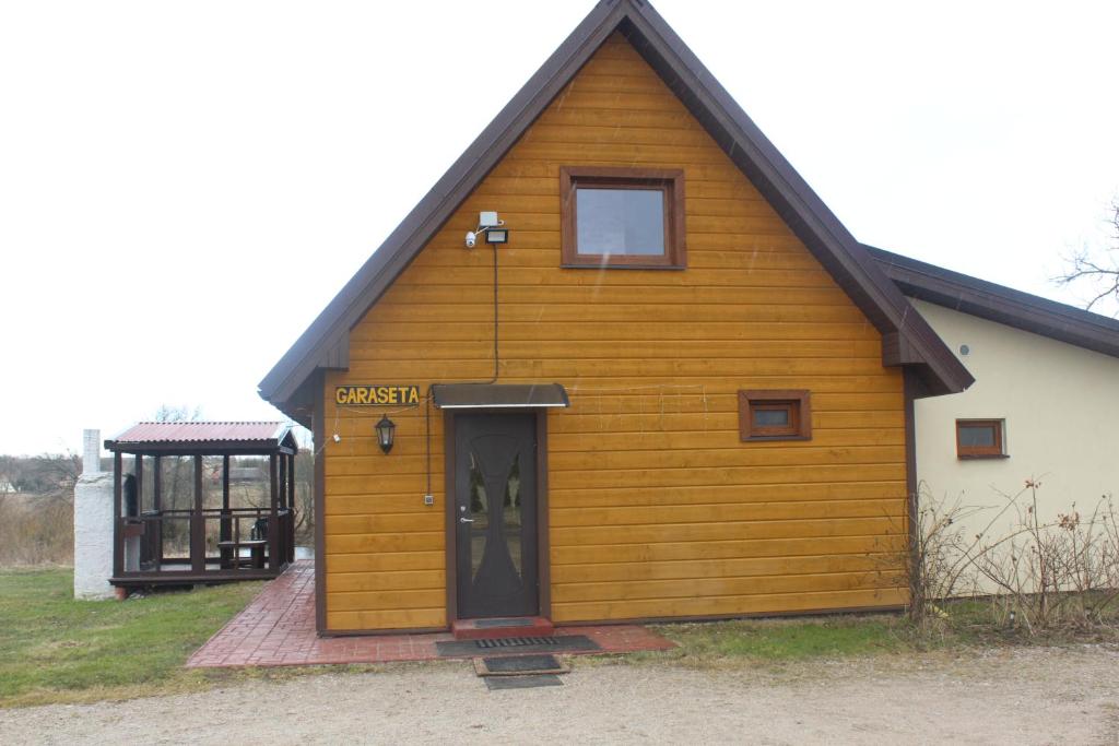 ein großes Holzhaus mit einer Tür und einem Fenster in der Unterkunft Garaseta in Kretinga