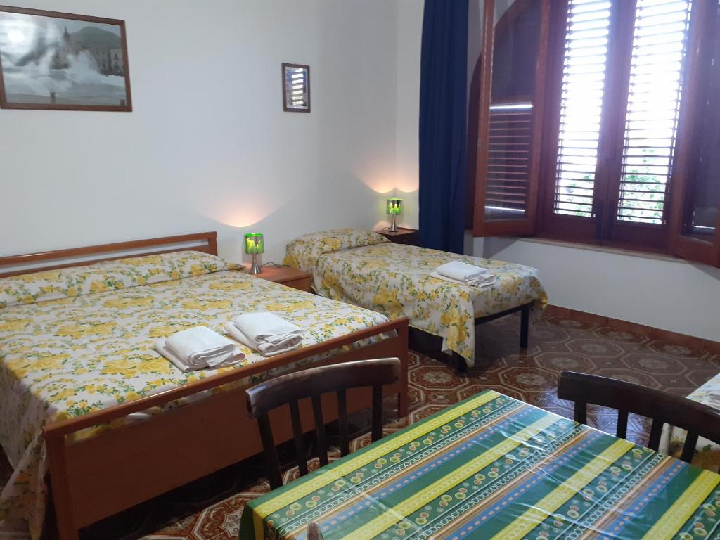 a hotel room with two beds and a table and chairs at Villa Rosa in Lipari