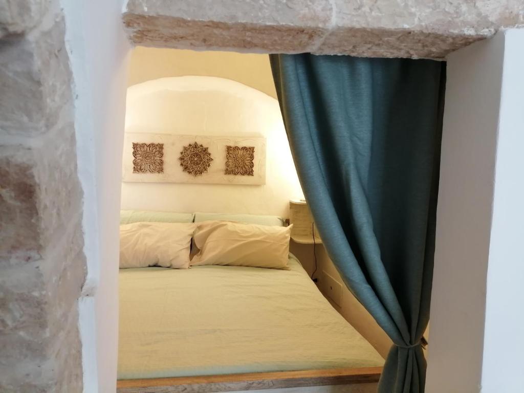 ein Schlafzimmer mit einem Bett und einem Fenster mit einem Vorhang in der Unterkunft Trulli Almadè in Alberobello