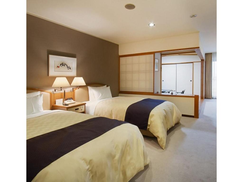 Dogo Onsen Funaya - Vacation STAY 54201v في ماتسوياما: سريرين في غرفة الفندق مع نافذة