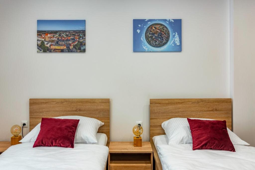 2 camas en una habitación con 2 almohadas rojas en Apartament Residence Nysa, en Nysa