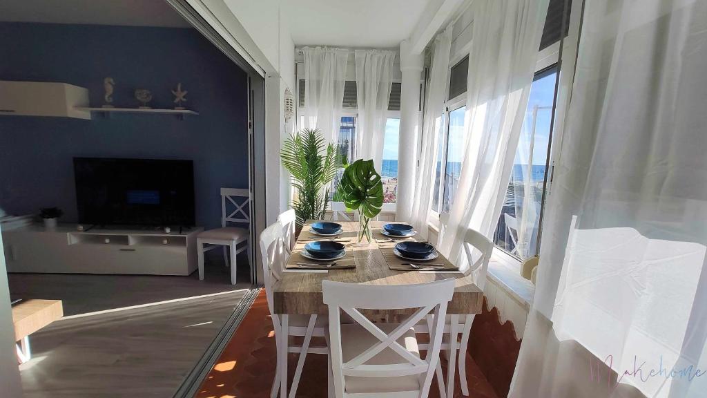 une salle à manger avec une table, des chaises et une grande fenêtre dans l'établissement En la misma playa nuevo 3 dormit vistas al mar, à Punta Umbría