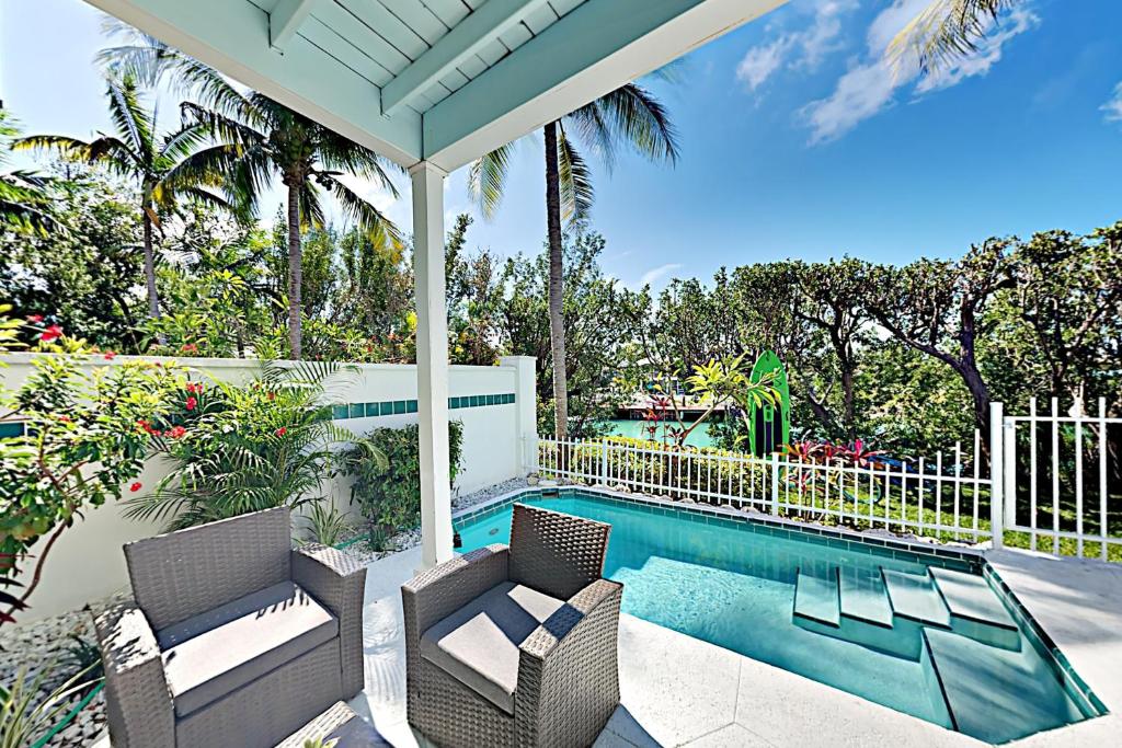 a house with a swimming pool and two chairs and a porch at Palm Villa in Duck Key