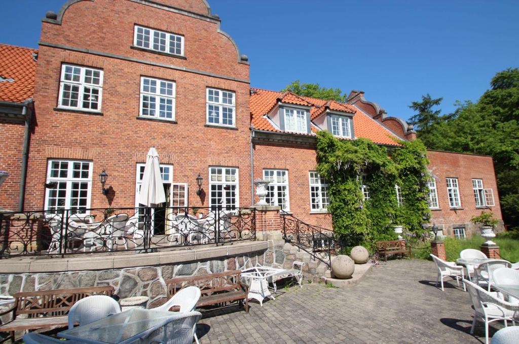 a large brick building with tables and chairs on a patio at Sauntehus Castle Hotel in Hornbæk