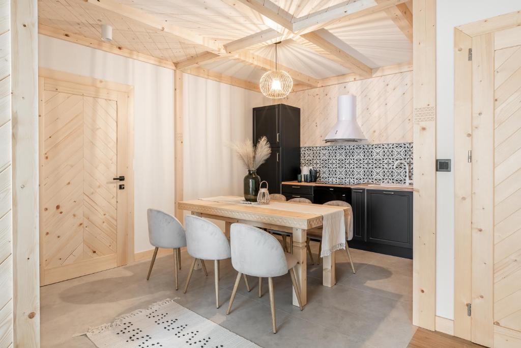 Folkova 21 - Apartamenty في بياى دوناجك: مطبخ مع طاولة خشبية وكراسي بيضاء