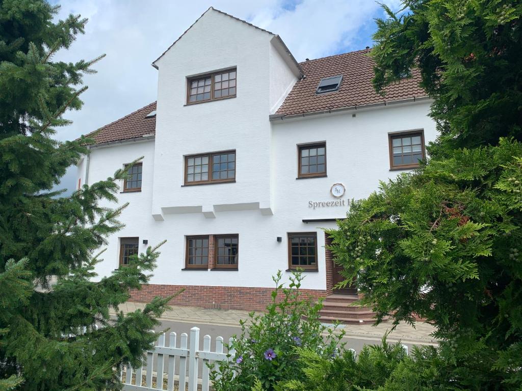 a white house with a white fence and trees at Spreezeit Hotel connect in Senftenberg