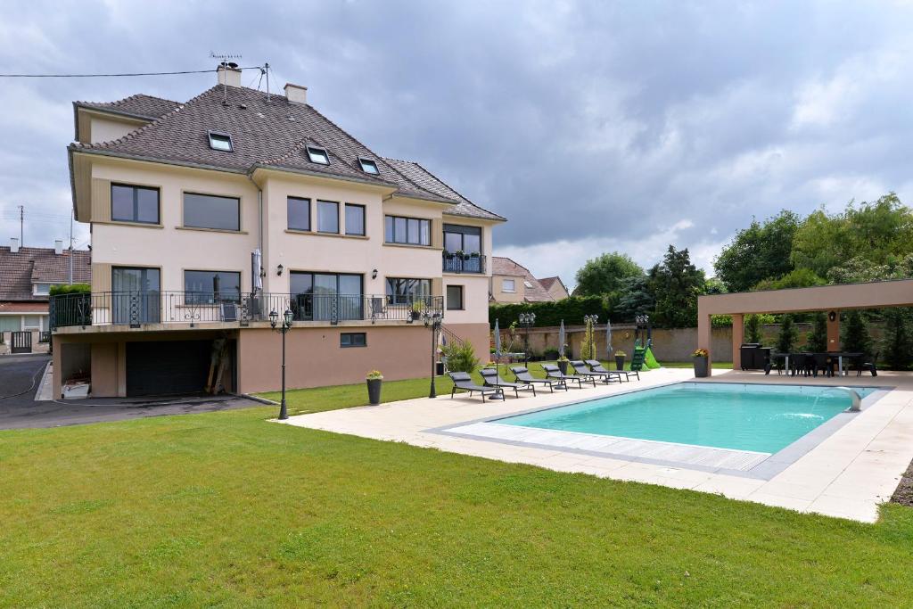a large house with a swimming pool in the yard at Chambres Vignes et Châteaux in Rouffach