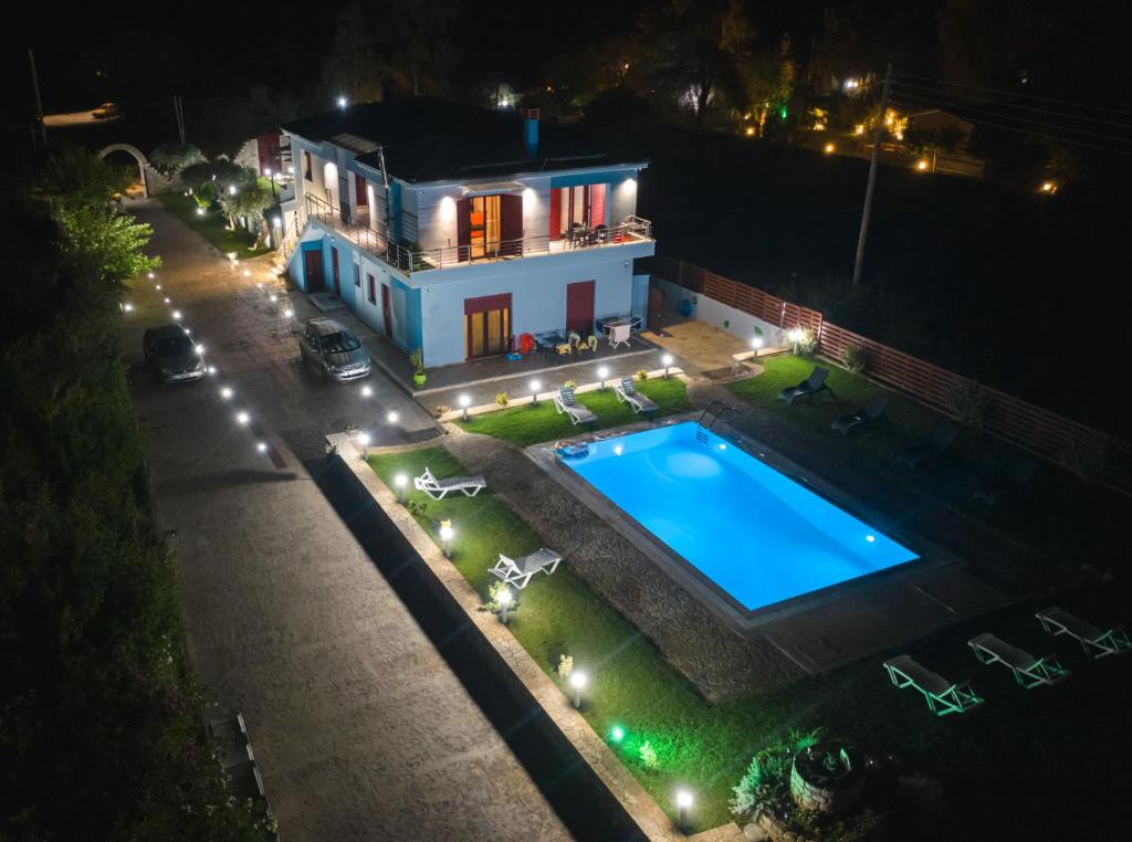 a swimming pool in front of a house at night at Olive Tree Suites in Eleonas