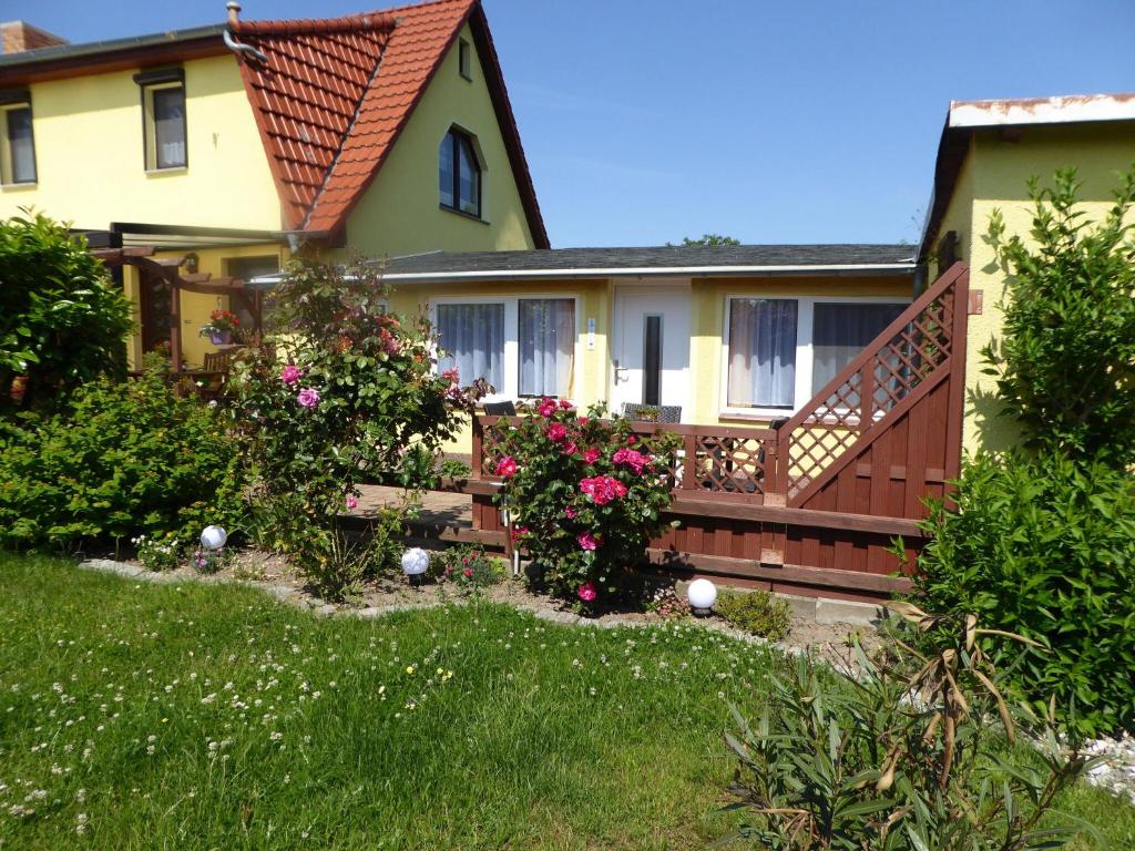 una casa con terraza y flores en el patio en Bungalow in Zweedorf mit Liegewiese, en Zweedorf
