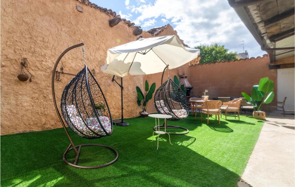 eine Terrasse mit Stühlen und einem Regenschirm auf Gras in der Unterkunft Awesome Home In San Pedro De Ceque With Wifi in San Pedro de Ceque