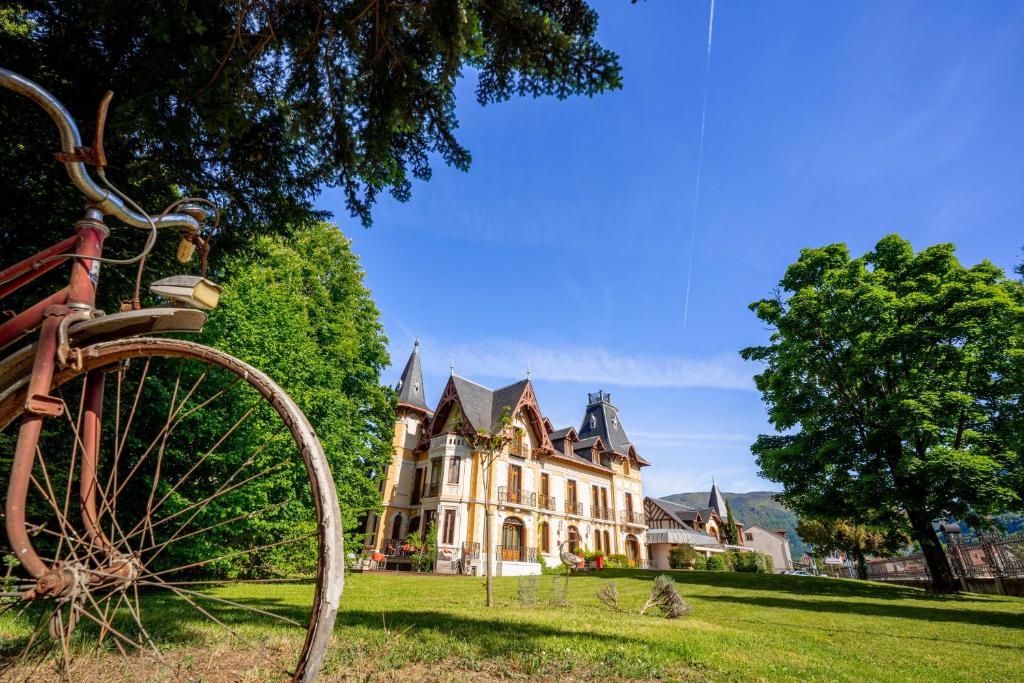 un vélo garé devant une grande maison dans l'établissement Le Manoir d'Agnès Logis hôtel restaurant, à Tarascon-sur-Ariège