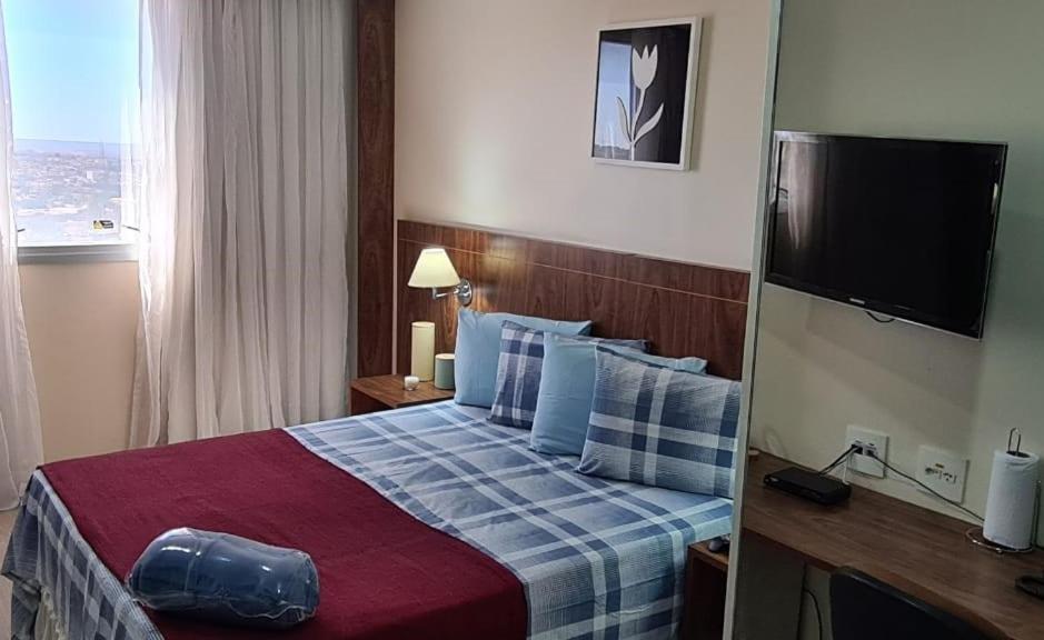 a hotel room with a bed and a television at Lindo Flat Aconchegante no Centro de Taguatinga in Taguatinga