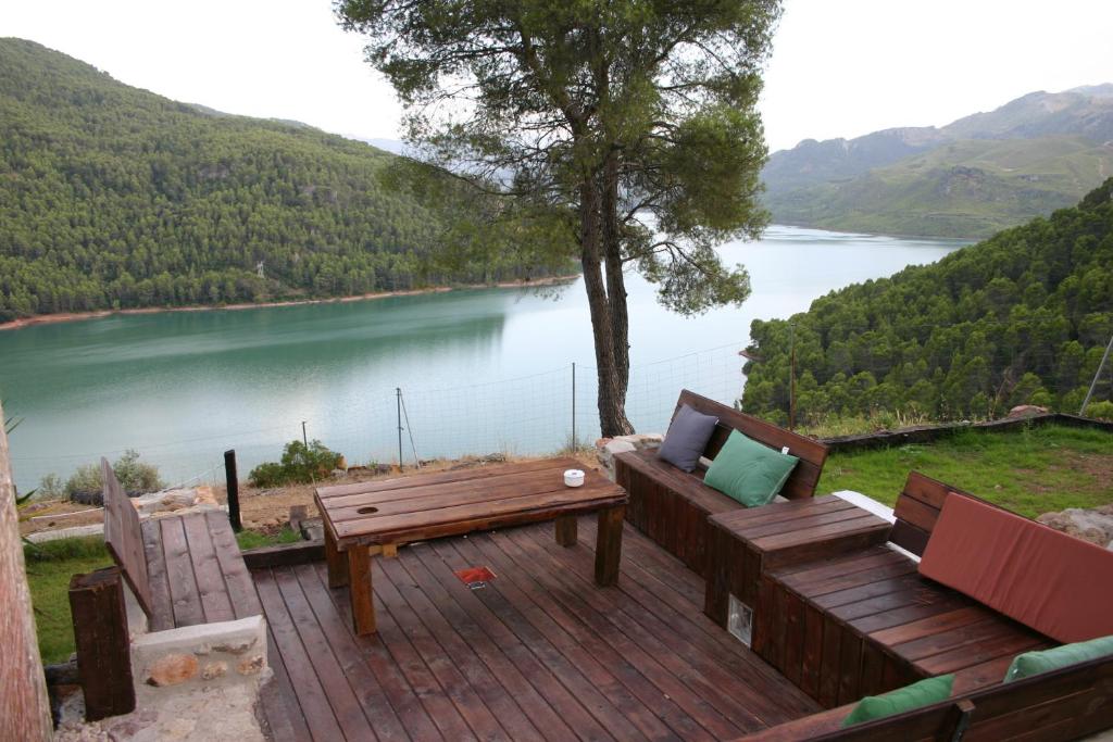 a wooden deck with a bench and a view of a lake at Casa Rural Los Parrales in El Tranco