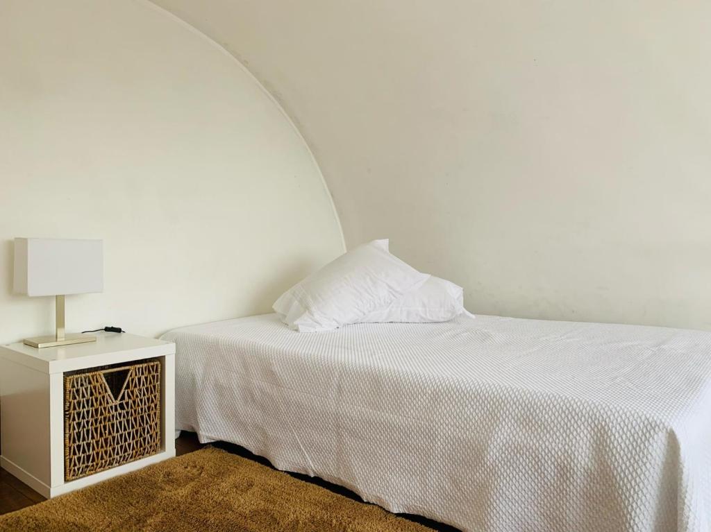 een witte slaapkamer met een bed en een nachtkastje bij Pérola de Viana - Cabedelo in Viana do Castelo