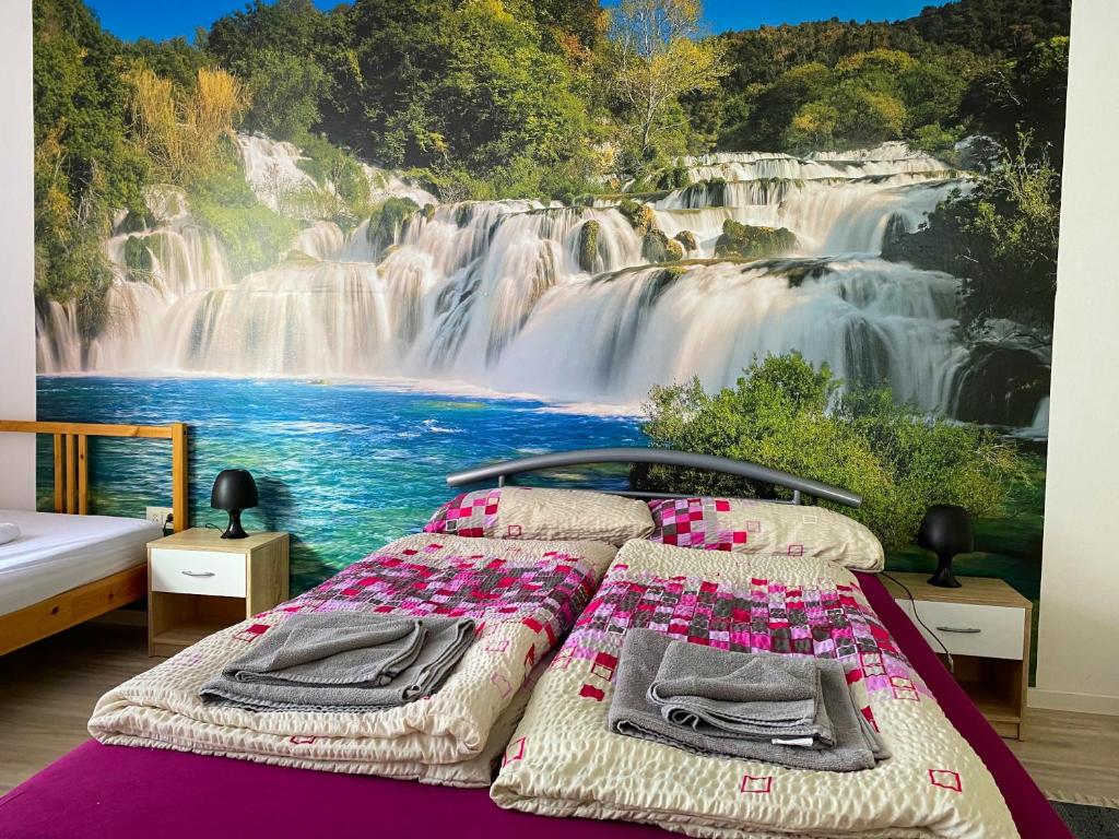 1 dormitorio con 1 cama con un mural en la pared de una cascada en Ferienwohnung Fischach, en Fischach
