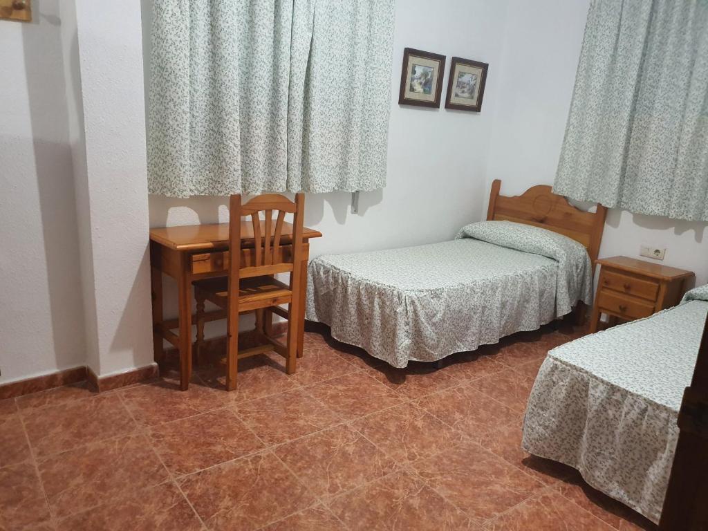 um quarto com 2 camas, uma mesa e uma secretária em Los Príncipes em Palos de la Frontera