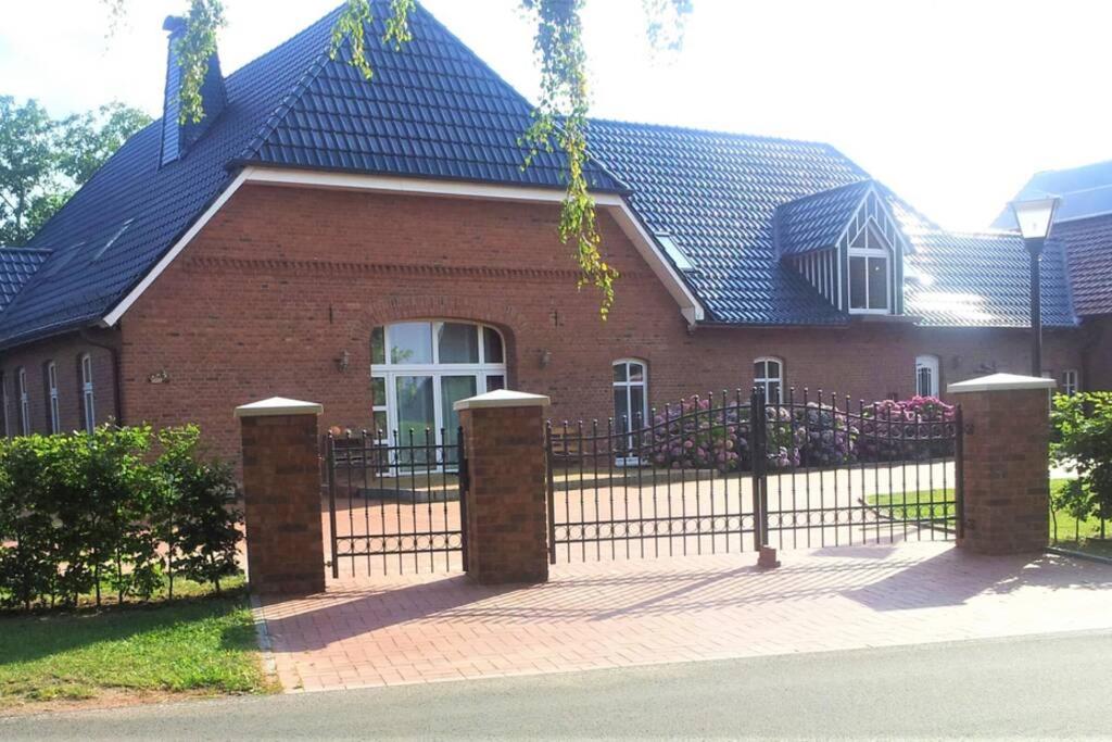 a red brick house with a black fence at Ferienwohnung Landhaus Auf dem Hollo in Petershagen