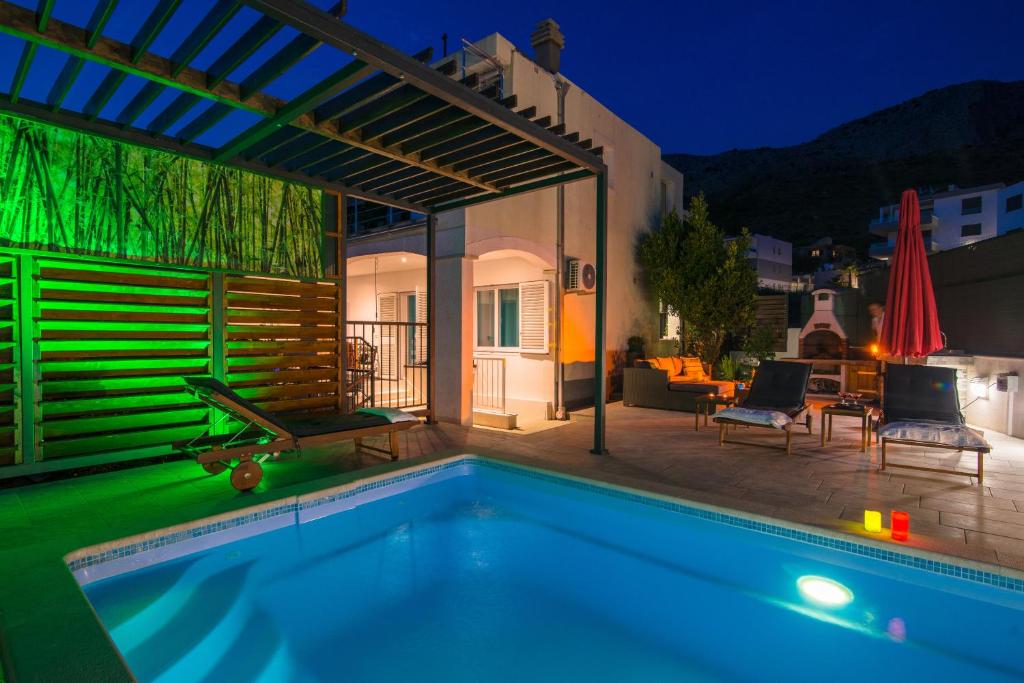 una piscina frente a una casa por la noche en Arky, en Podstrana