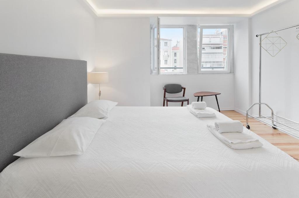a white bedroom with a large white bed with white sheets at Room With Private Bathroom -Alcantara in Lisbon