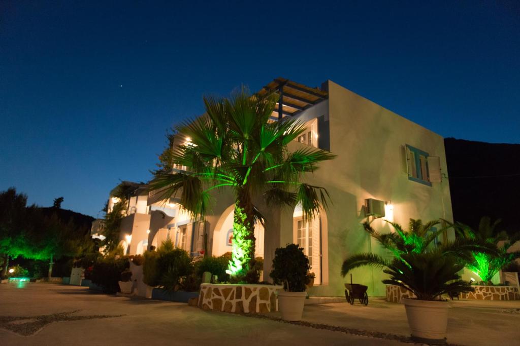 a building with a palm tree in front of it at night at Elpiniki in Alinda