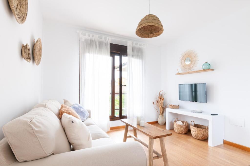 un soggiorno bianco con divano bianco e TV di Apartamento Las Ocas "Solo Adultos" a Muros de Nalón