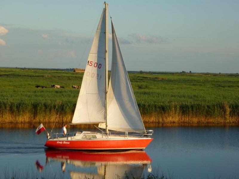 a red and white sail boat on the water at Siedlisko Nad Rozlewiskiem in Świnoujście