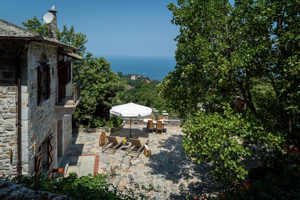 patio ze stołem, krzesłami i białym parasolem w obiekcie Helene Eco Luxury Villa w mieście Tsagarada